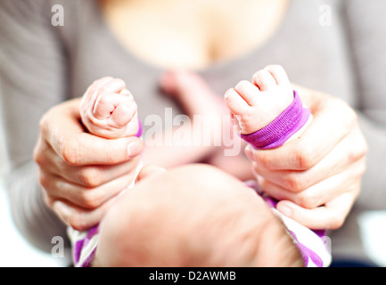 Overhead cropped view of a mother holding a tiny baby's hands in her own with focus to the hands Stock Photo