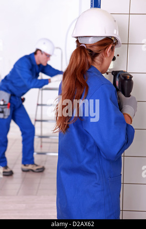 Female electrician drilling a wall Stock Photo