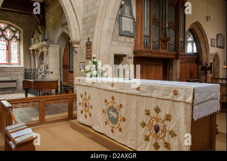 Close-up of chancel altar (embroidered cloth & crucifix) archways & organ pipes - interior of Church of Saint Mary, Masham, Yorkshire, England, UK. Stock Photo