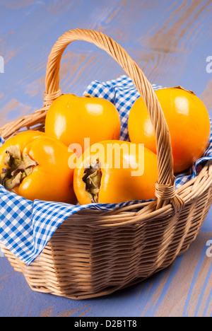 Delicious ripe persimmon fruit inside a traditional basket Stock Photo