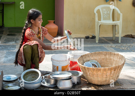 Teenage Indian girl washing dishes outside her rural indian village home. Andhra Pradesh, India Stock Photo