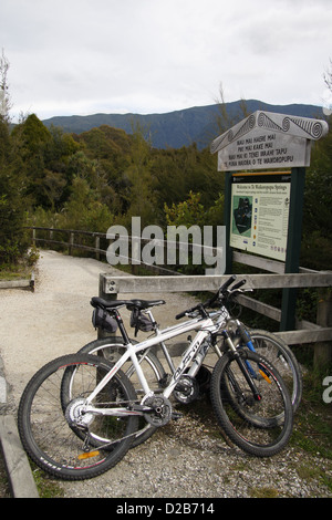 Visitors' bicycles park next to the sign for the Te Waikoropupu Springs Scenic Reserve. Stock Photo