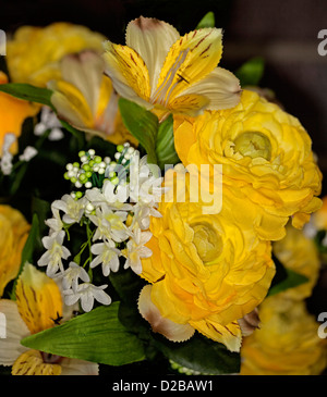 Bouquet of beautiful artificial / silk roses and other flowers - bright yellow and white - against a dark background Stock Photo