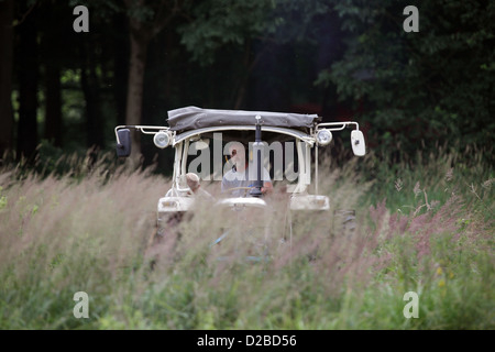 Resplendent village, Germany, farmer on a tractor crossing a meadow Stock Photo