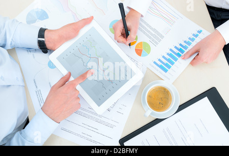 Business team analyzing income charts and graphs with modern digital tablet. Top view photoshoot. Stock Photo