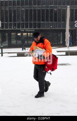 Postman in snowy weather, Coventry city centre, UK Stock Photo