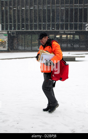 Postman in snowy weather, Coventry city centre, UK Stock Photo