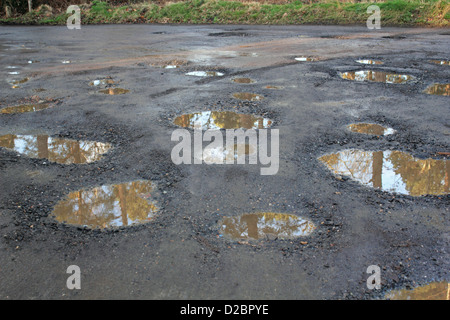 Water filled pot holes in a woodland car park. Surrey England UK. Stock Photo