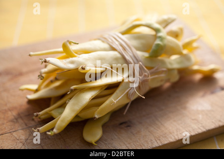 A bundle of organic golden coloured runner beans on a cutting board Stock Photo