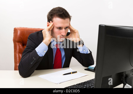 Young concerned businessman in the office looking at computer display and thinking about business problems. Stock Photo