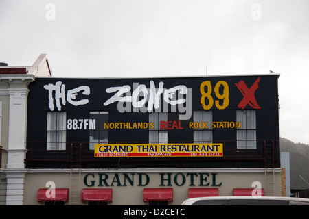 Advertising banners for Zone 89X a radio station for a Thai restaurant on the house front of the Grand Hotel in Whangarei. Stock Photo