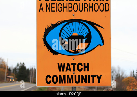 A neighborhood community watch sign beside a road with school bus in the diatance Stock Photo
