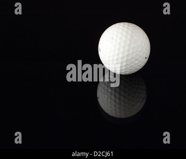 A golf ball reflecting on a black surface. Stock Photo