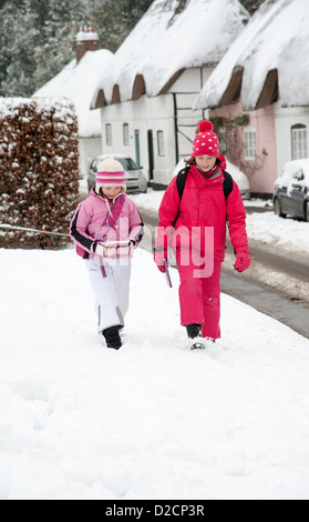 Children walking to school in a rural village in Hampshire England UK  Along snow covered street Stock Photo