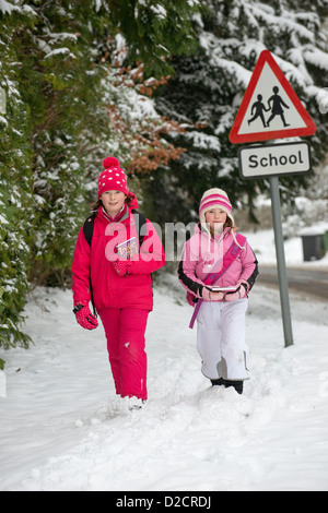 Children walking from school along a snow covered road Hampshire UK Stock Photo