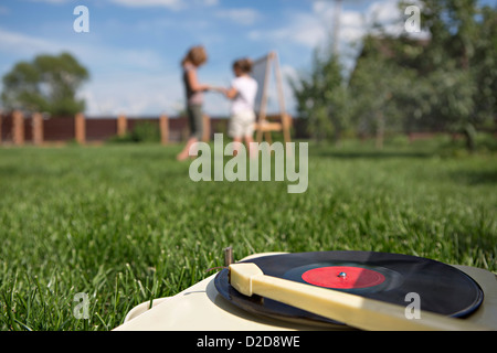 An old-fashioned record player on a lawn, children in background Stock Photo