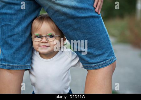 A baby girl holding herself up in between her mother's legs Stock Photo