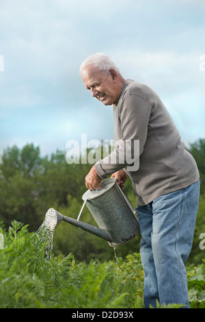 A senior man watering plants in his garden Stock Photo