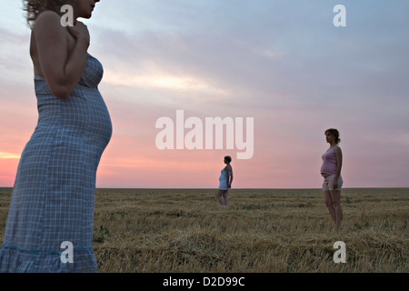 A composite image of three versions of the same pregnant woman in a field Stock Photo