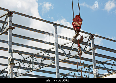 A crane hook attached to cables at a construction site Stock Photo