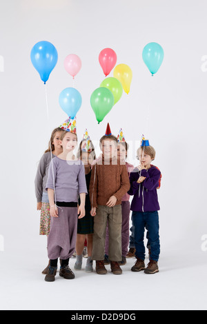 A group of kids wearing party hats and holding balloons Stock Photo - Alamy