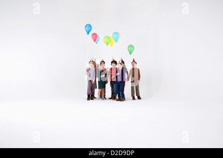 A group of kids wearing party hats and holding balloons Stock Photo - Alamy