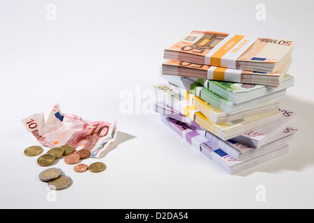 Stack of large billed Euro banknotes next to a crumpled ten note and change Stock Photo