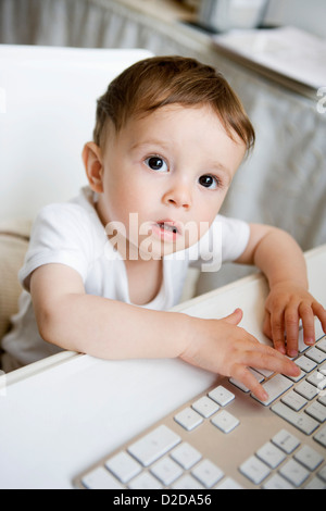 A toddler playing with a computer keyboard Stock Photo