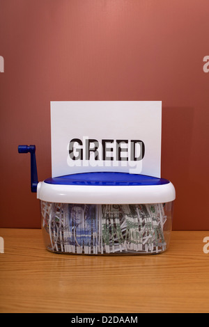 Money being shredded with the word 'greed' on top of the page Stock Photo