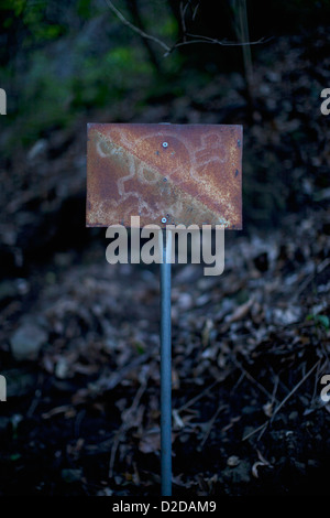An old rusty sign with a skull and crossbones on it posted outdoors Stock Photo