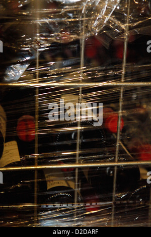 A metal crate filled with stacked red wine bottles and wrapped in plastic wrap Stock Photo