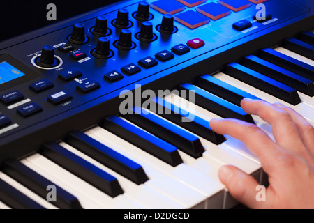 Close up of a hand playing a MIDI controller keyboard. Stock Photo