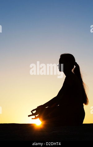 Sunset silhouette of an Indian girl meditating. Andhra Pradesh, India