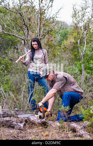 Woodworkers sawing branch of fallen oak tree, male, 40 years, Caucasian, female, 18 years, Caucasian, chainsaw, ax, Texas, USA Stock Photo