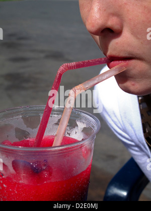 young girl drinking slushy through straw Stock Photo
