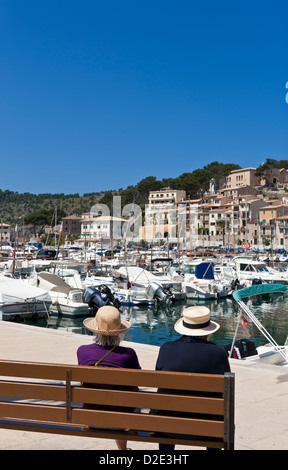 MALLORCA Elderly Holiday Spain Two ladies with straw sun hats sitting on a bench together enjoying harbour view Port de Soller Palma de Mallorca Spain Stock Photo