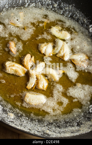 Smashed garlic cloves frying in butter and oil Stock Photo