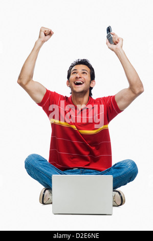 Cheering man with laptop sitting cross-legged Stock Photo - Alamy