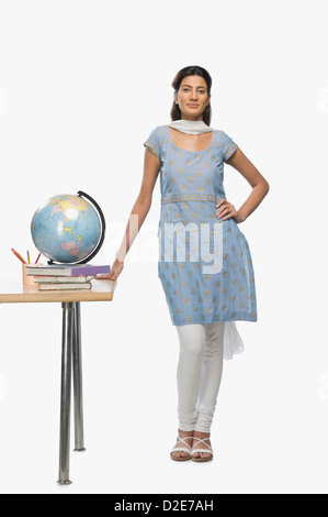 Female teacher standing beside a desk Stock Photo