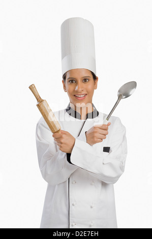 Female chef holding a rolling pin and a ladle Stock Photo