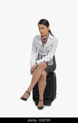 Air hostess sitting on her luggage and thinking Stock Photo