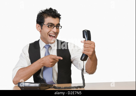 Businessman pointing at a telephone receiver and smiling Stock Photo