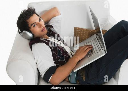 Man listening to headphones while using a laptop Stock Photo