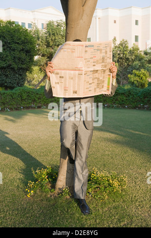 Businessman reading a newspaper in a park Stock Photo