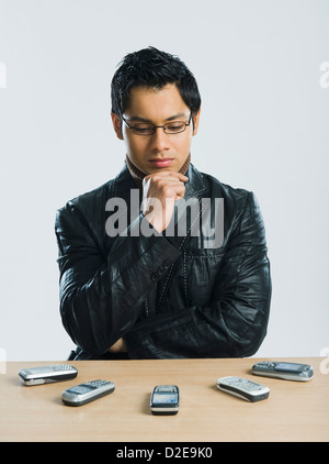 Man looking at mobile phones and thinking Stock Photo