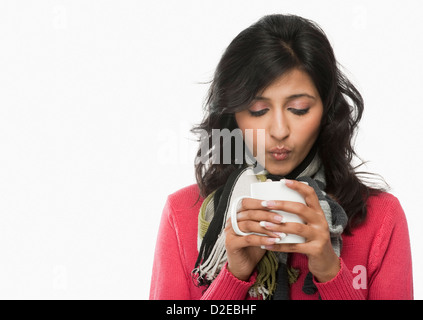 Woman blowing into a coffee cup Stock Photo