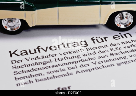 Detail photo of a Car sales agreement in German, alongside is a model car Stock Photo