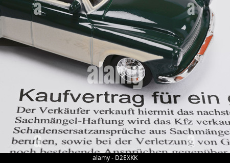 Detail photo of a Car sales agreement in German, alongside is a model car