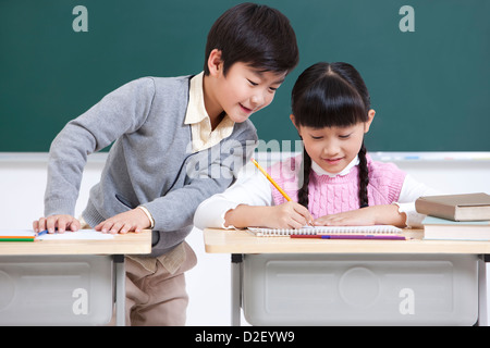 Happy schoolchildren doing homework in classroom Stock Photo