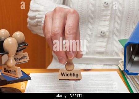 a stamp with the German inscription important is held in the hand Stock Photo